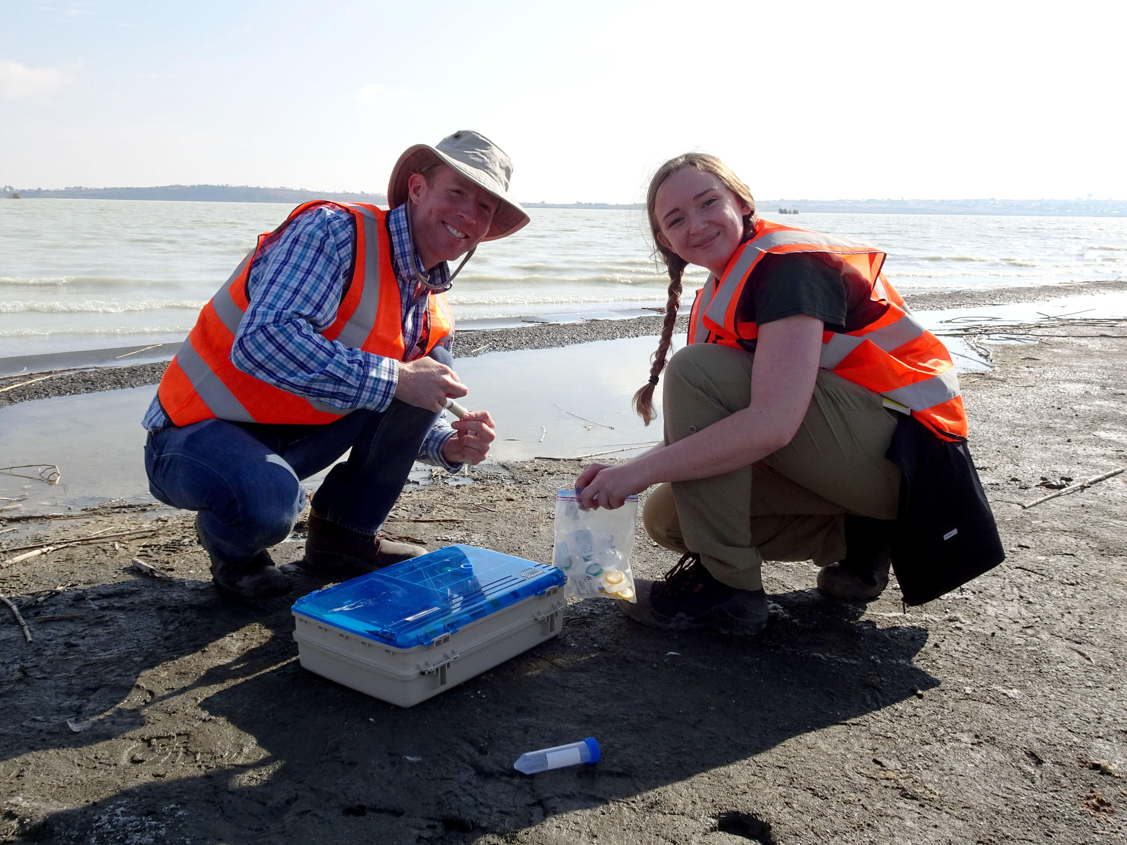 A student and Dr. Ian Power smiling at the camera while collection samples from a beach