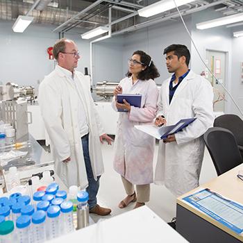 Students speaking with a professor in a Chemistry lab. 