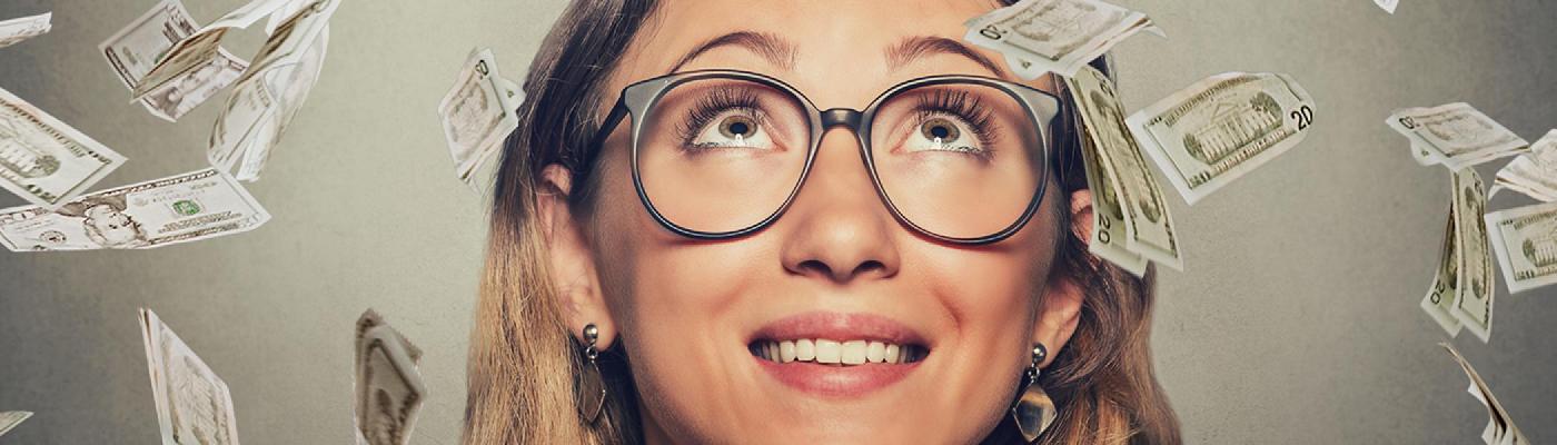 Young woman looking up, money falling down