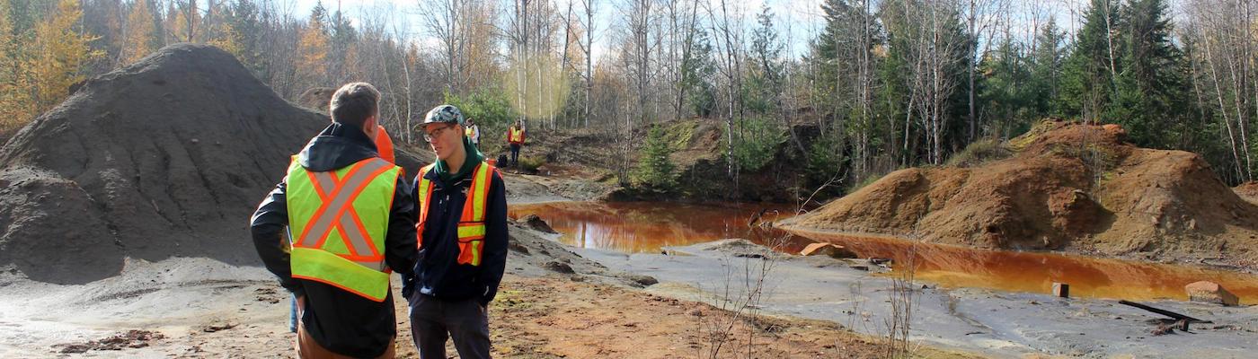Two people in safety vests conversing in a quarry