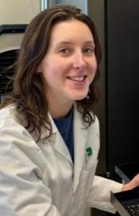 person with pale skin and dark hair wearing a white coat