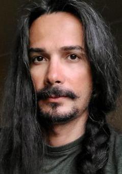 person with long dark hair and mustache