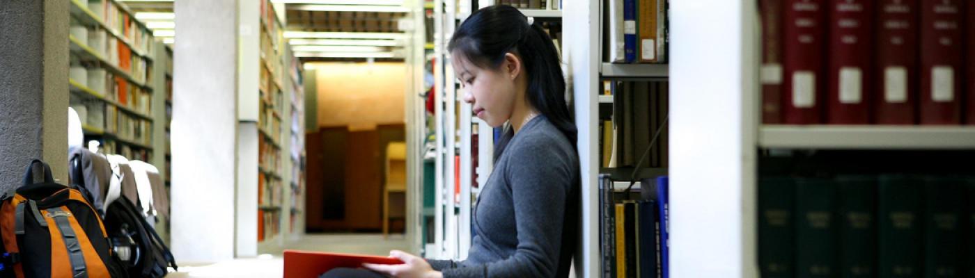 girl writes down notes while sitting in the library
