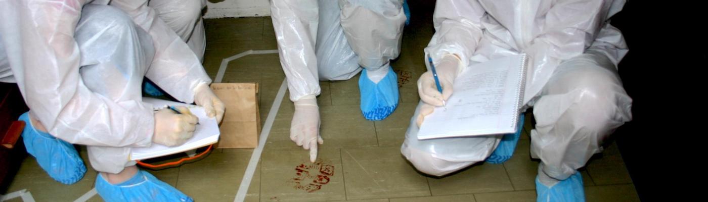 3 students kneeling on the ground analyzing blood