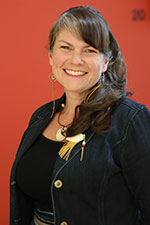 Woman with jacket and long hair smiling against a red background. 