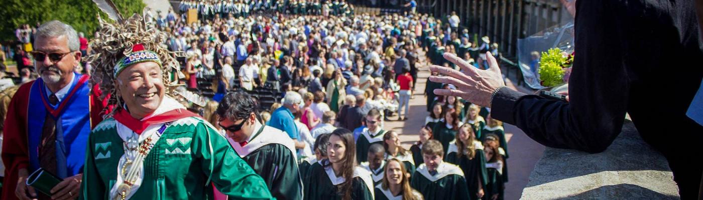 A group of student and professors leaving the Bata library podium in a crowd following an indigenous convocation on a summer's afternoon