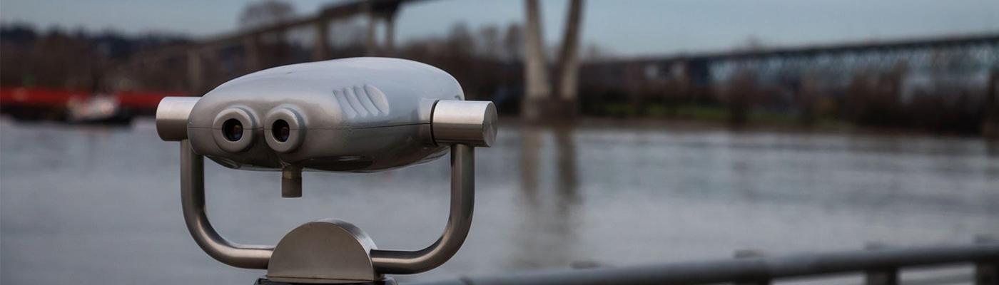 scenic lookout binoculars in foreground, river and bridge in the background