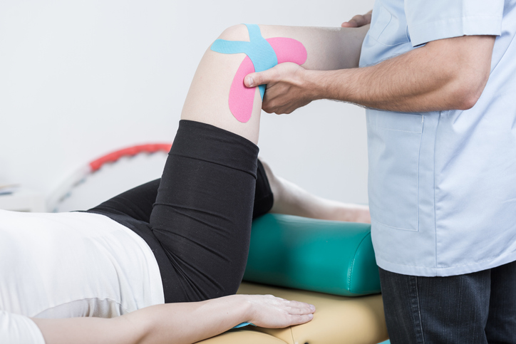 Kinesiology tape on a person's knee in physiotherapy session