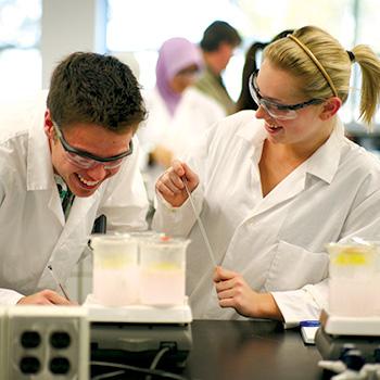 Students in labcoats working in lab