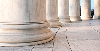 The bases of large exterior columns in a row on a tiled floor