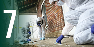 Forensics student in full forensics gear investigating a crime scene