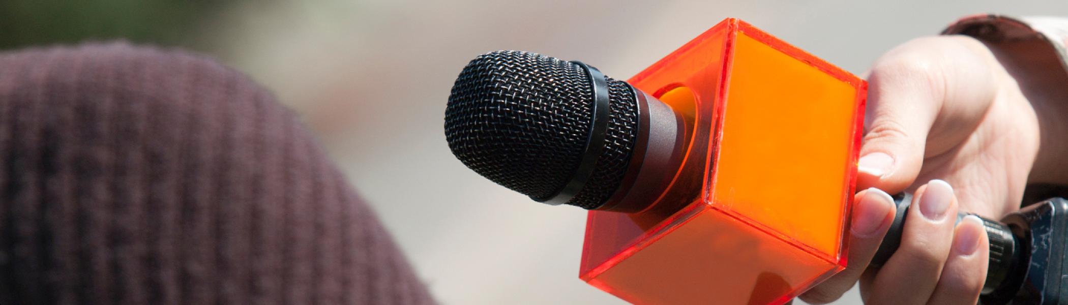 Microphone being held with orange square collar on it