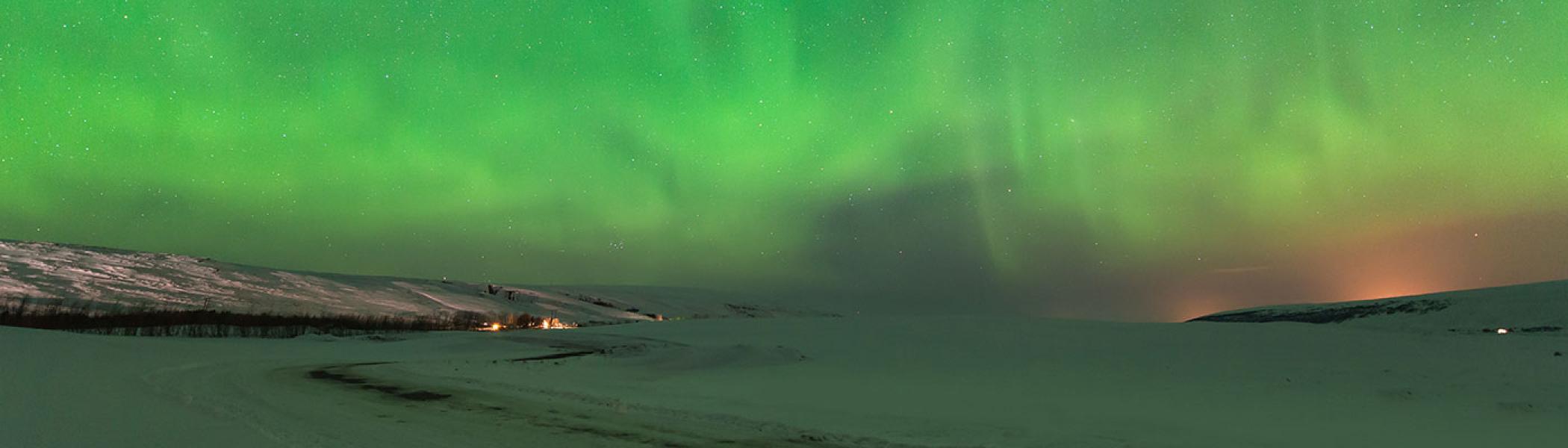 Landscape of a frozen lake and the green northen lights at night