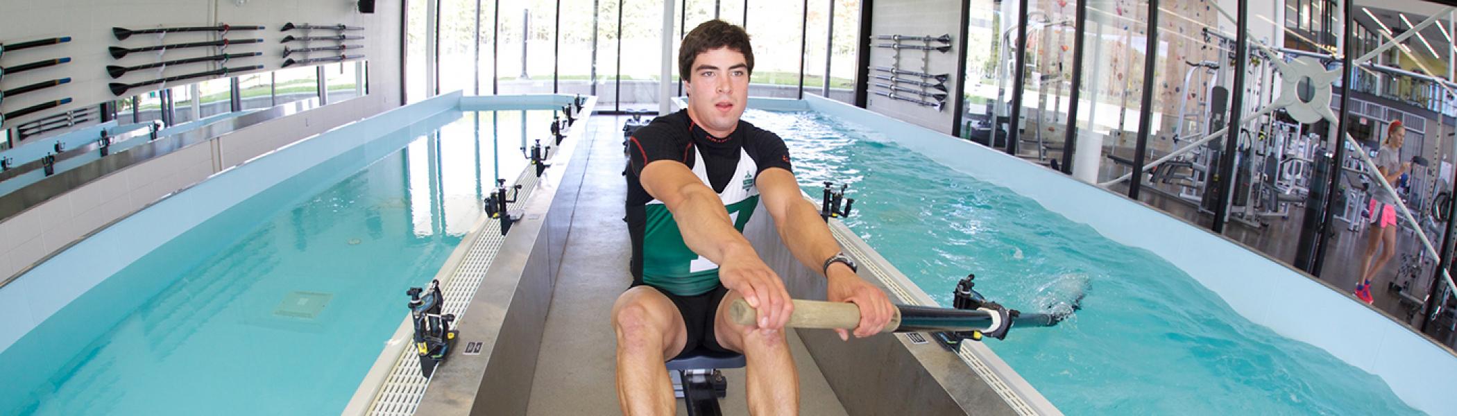 Student in the rowing tank at the Athletic Centre practicing his strokes
