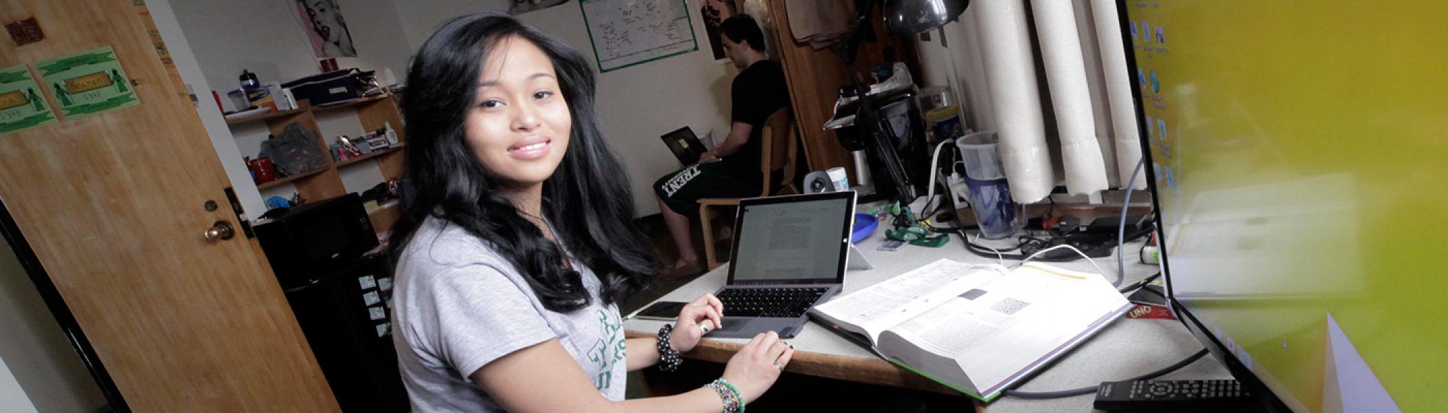 Student working on laptops in Lady Eaton College dorm room