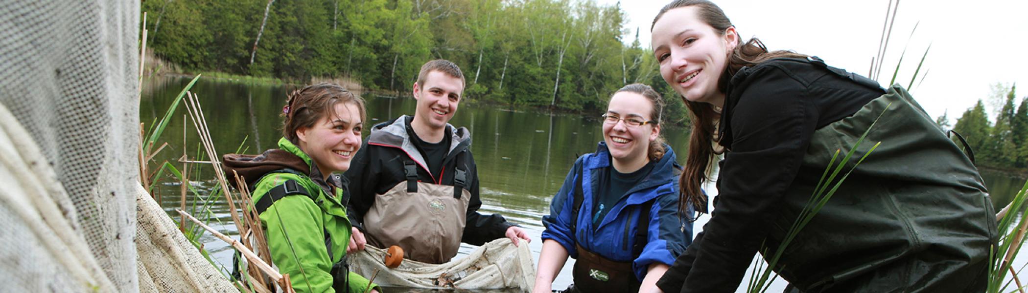 Students standing in a river on a cloudy day gathering river samples