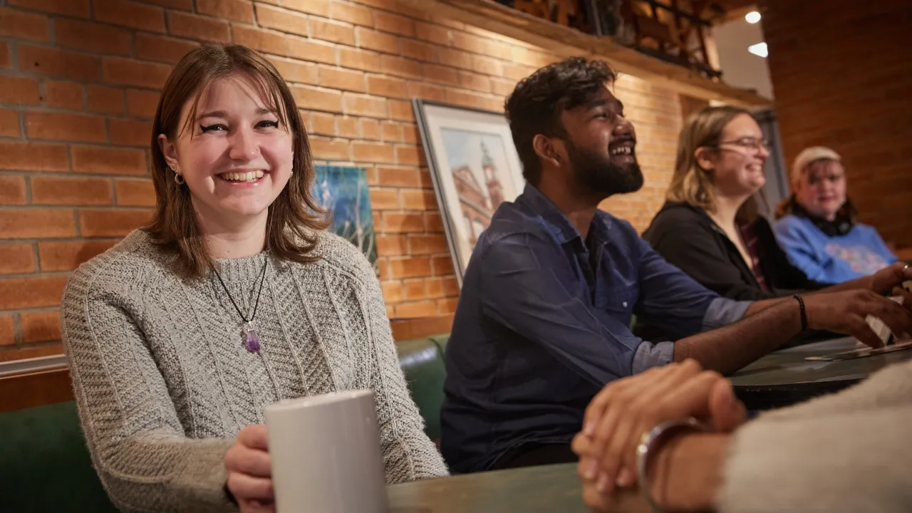 Student in the Trend, holding a coffee mug and smiling at the camera.