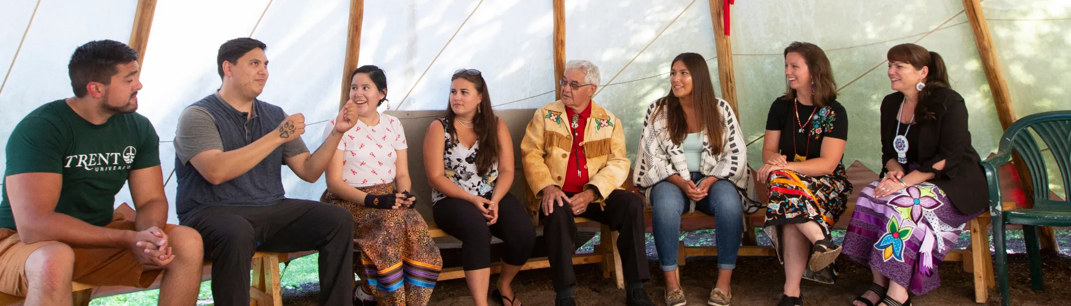 Group of Trent University First Peoples House of Learning staff and students talking inside of a tipi.