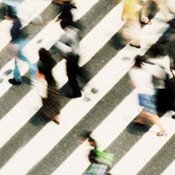 Birds eye view of people walking on a busy sidewalk. The people are blurred