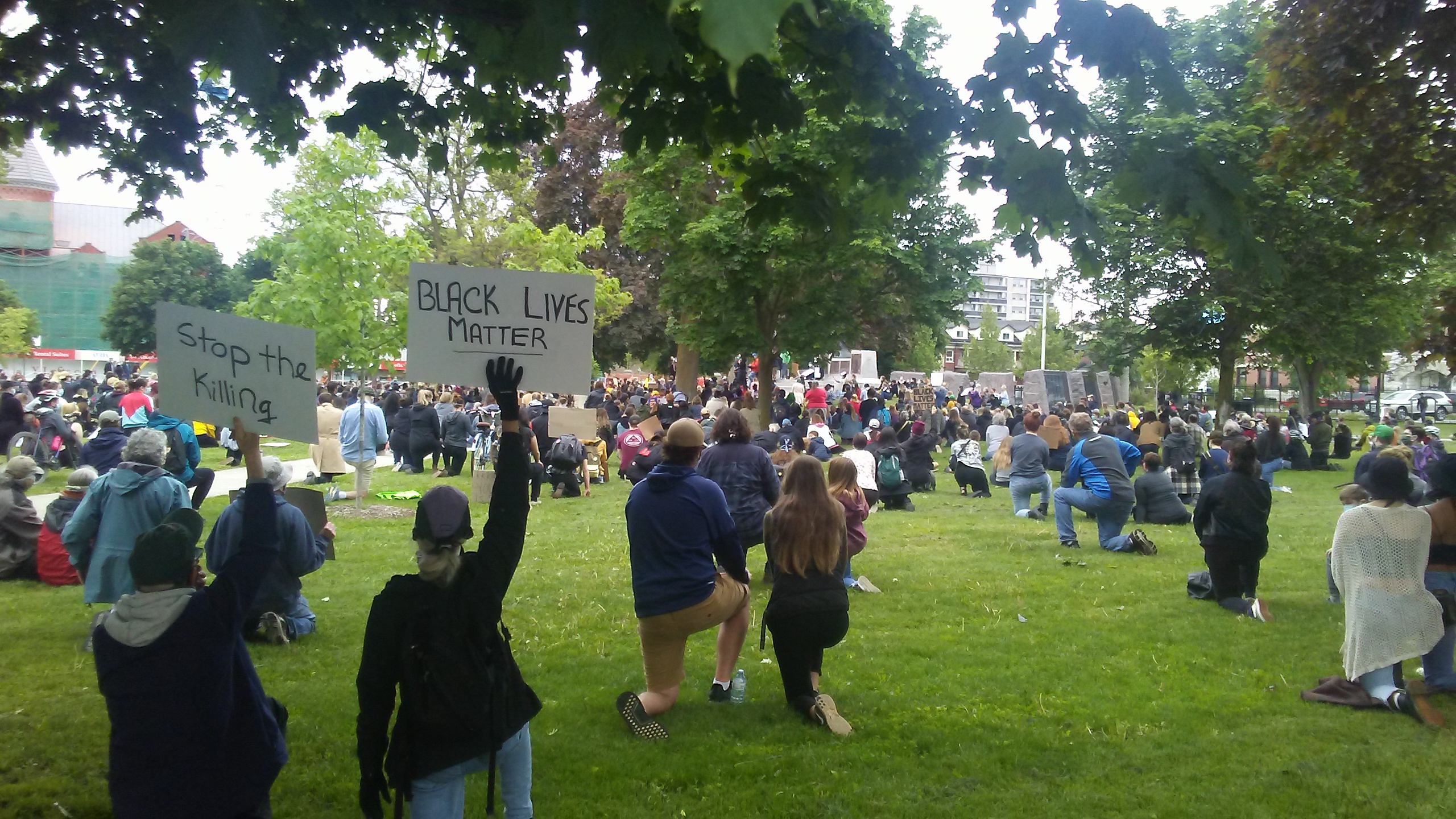 two people holding up signs that say "stop the killing" and "black lives matter" in a crowded park