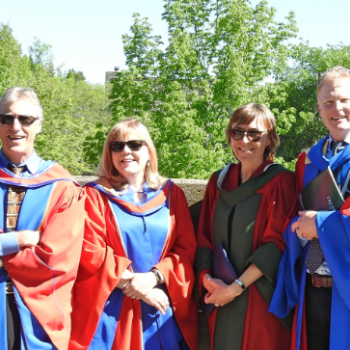 faculty members peter lafleur, cheryl mckenna neuman, catherine eimers and stephen hill at convocation wearing gowns smiling at camera on sunny day