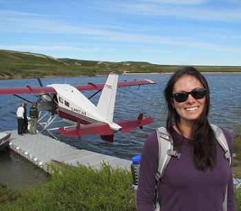 female student standing in front of a seaplane docked in a bay