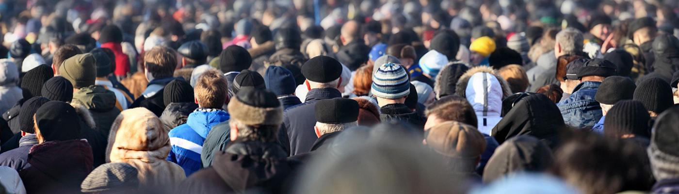 Close-up of school globe.Large crowd walking away from the camera, only the backs of heads are visible.