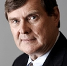 Ian Lord with short brown hair wearing a suit, smiling into the camera