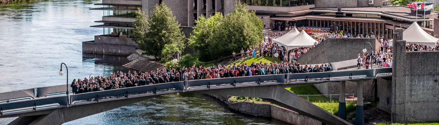 graduate students standing on bridge