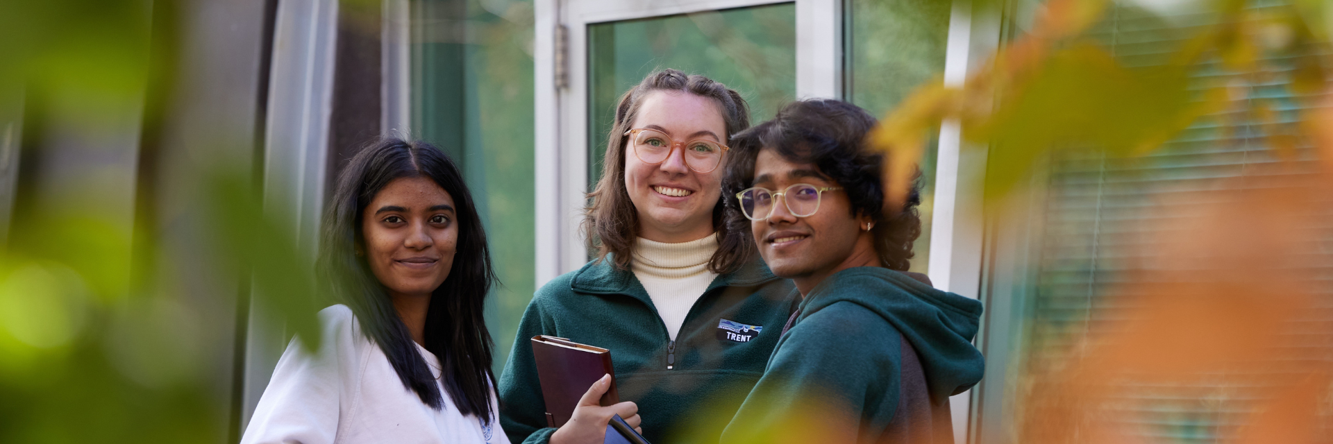 Three students outside smiling at the camera
