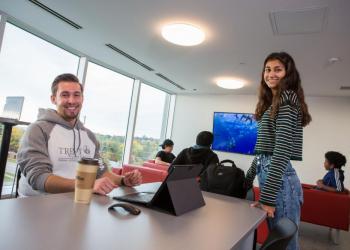 Students standing and sitting around a table