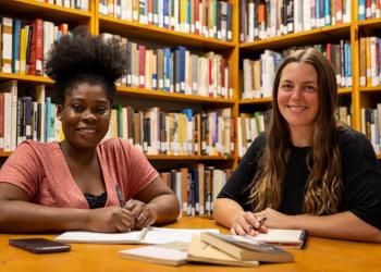 Two women studying together in a library