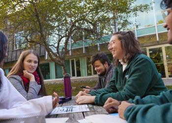 Students sitting around a picnic table outside