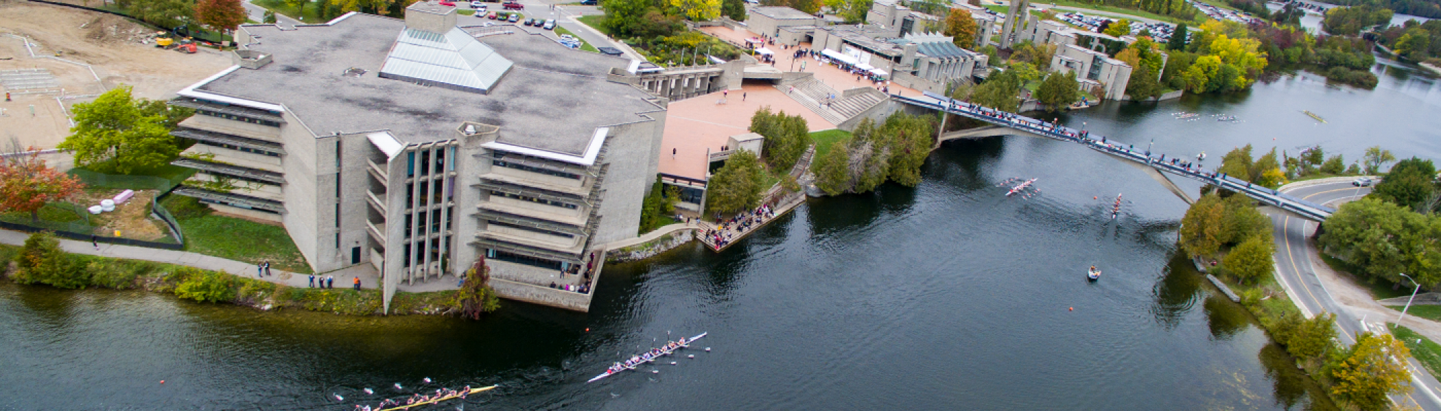 Aerial view of the Bata library, Faryon bridge and the Otonabee river in the fall, with boats rowing down it