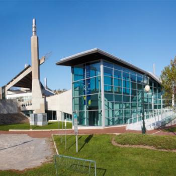 Front image of the Chemical Science Building with emphasis on the large glass entrance way and tower to the left 