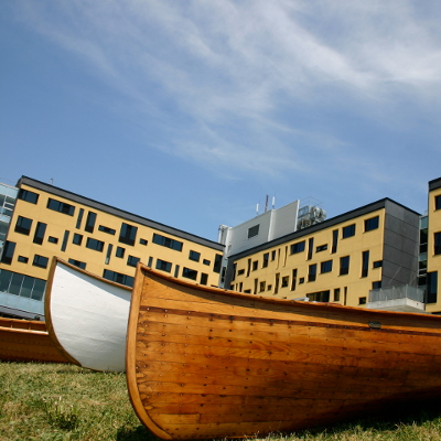 Exterior of Gzowski College from a distance with student made canoe's in front