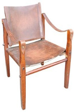 A rustic wooden base of four land hold the aged leather back seat and arm rests in place with metal nails