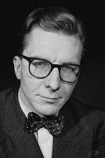 A black and white protrait of Robin Day wearing glasses, bow-tie, and styled hair