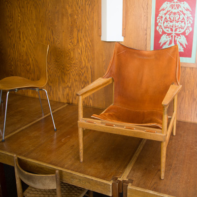 An original Ron Thom chair with natural leather backing and seat and wide wooden armrests 