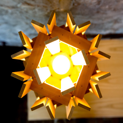 Wooden light fixture hung from the ceiling with interlocking wood planks making a angled pattern
