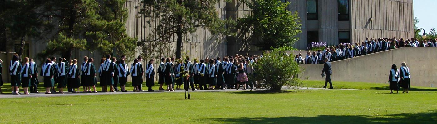 A long line of history graduates waling past Lady Eaton College in their convocation gowns
