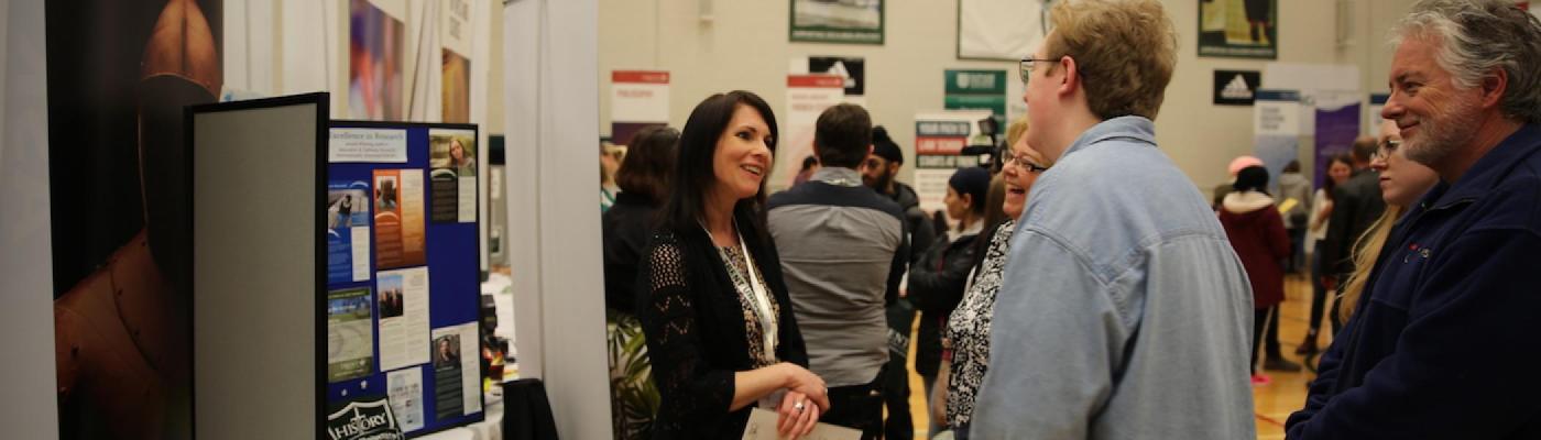 A woman talking to prospective students at the Trent University fair