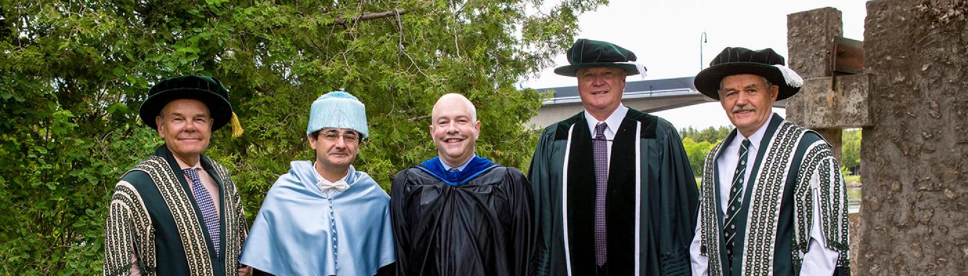 Convocation award winners posing with Dr. Don Tapscott and Leo Groarke in front of the Faryon bridge