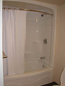White bathtub and shower with a white half open curtain