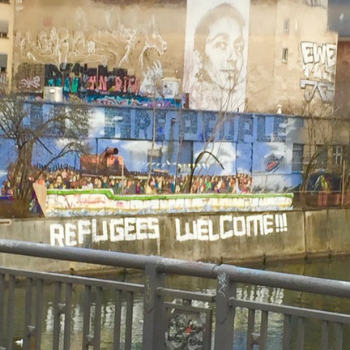 Bridge over a canal with Refugees Welcome painted on a wall