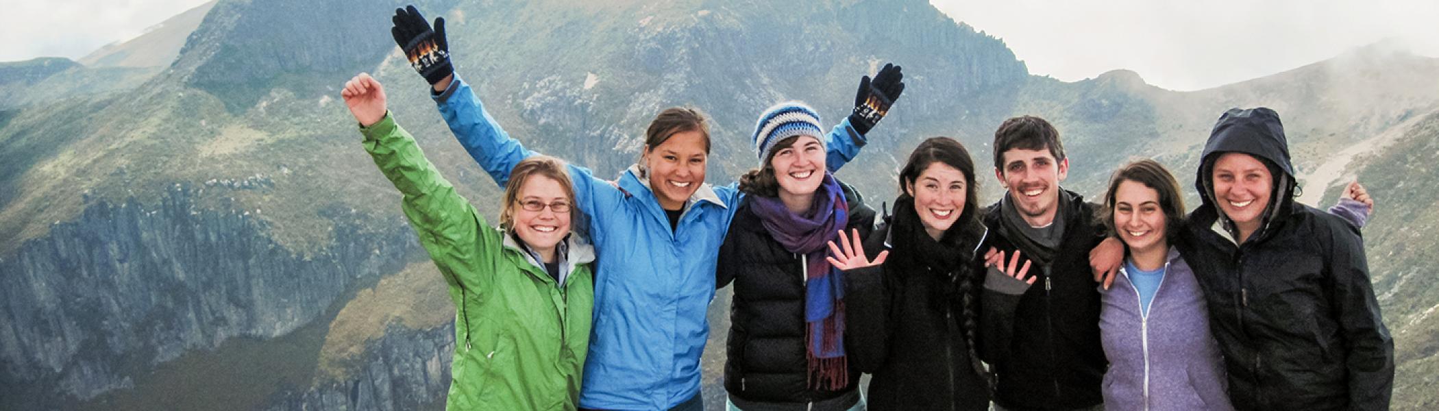Group of 7 students standing on a mountain smiling at the camera