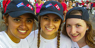 Students in baseball caps, smiling at the camera in a crowded Cuban street