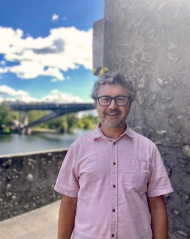 Professor standing on campus with a bridge in the background