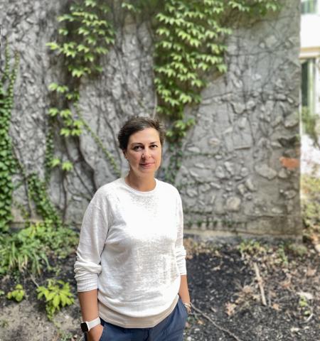 Professor on campus in front of a stone wall with ivy