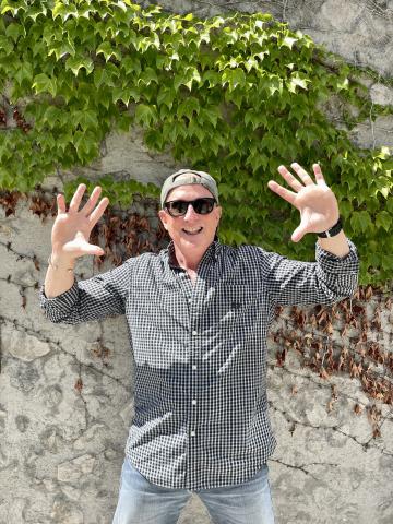 Professor on campus standing in front of a wall of ivy plants